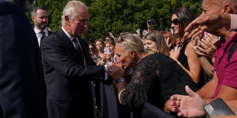 Una mujer saluda a Carlos III, frente al Palacio de Buckingham, ayer.
