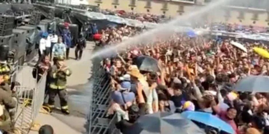 Bomberos rocían agua a asistentes del concierto de Grupo Firme en el Zócalo ante altas temperaturas.