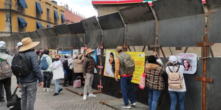 Integrantes del colectivo Voz de los desaparecidos de Puebla colocan fotografías de víctimas en vallas metálicas instaladas en Palacio Nacional este lunes