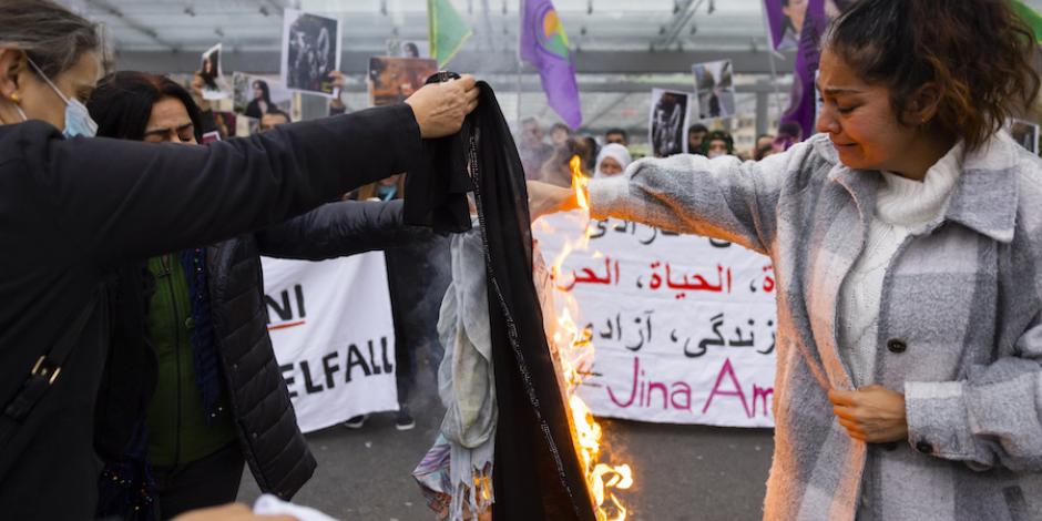 Mujer iraní, entre lágrimas, quema su velo durante una protesta en Suiza.
