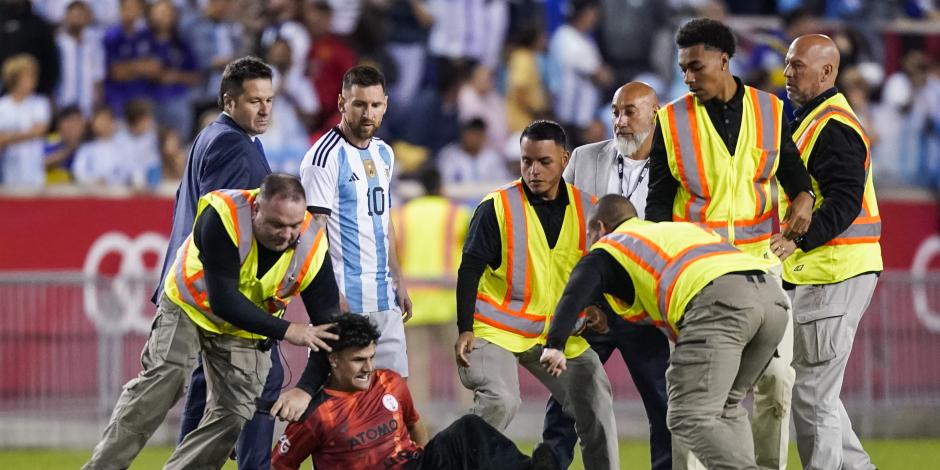 Lionel Messi observa al aficionado que fue derribado por la policía al final del partido amistoso entre Argentina y Jamaica.