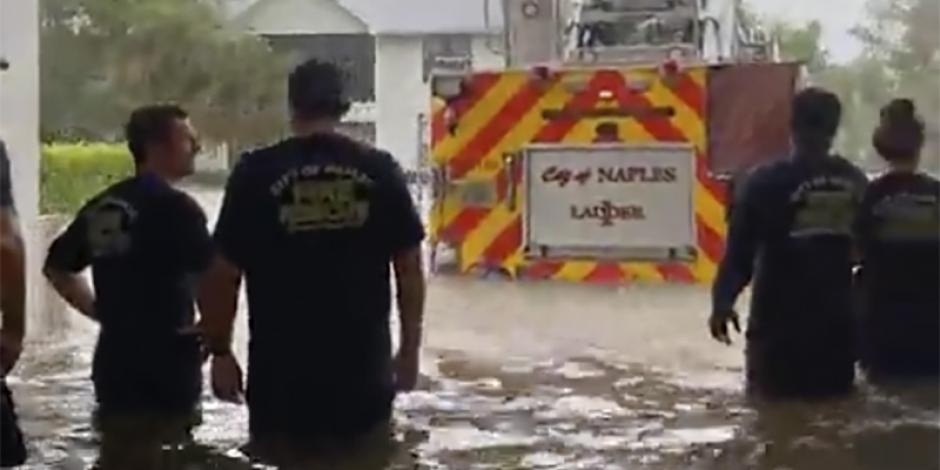 Bomberos observan su camión que se encuentra bajo el agua en Naples, ayer.