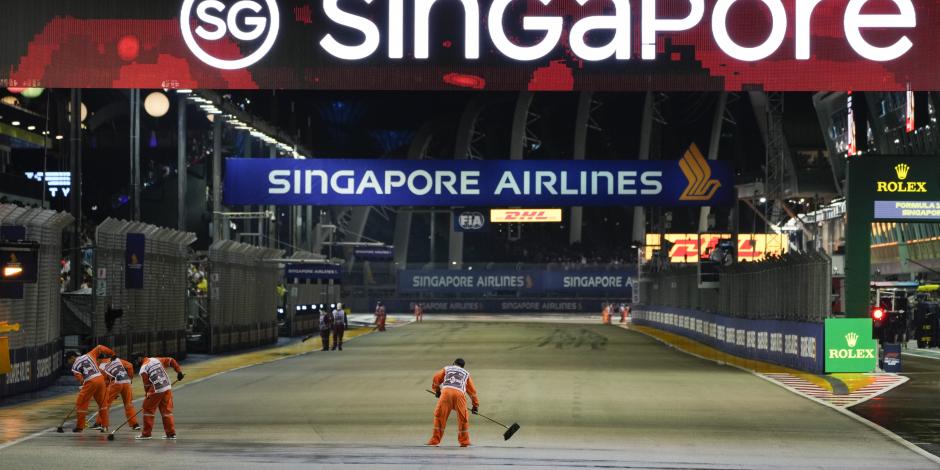 Los alguaciles limpian la pista de agua superficial después de que la lluvia retrasara el inicio del Gran Premio de Singapur de F1.