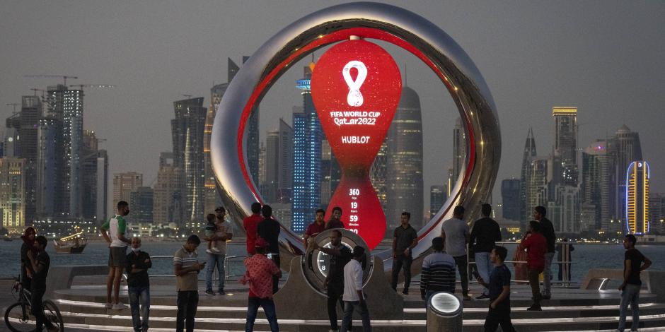Gente reunida alrededor del reloj de la cuenta regresiva oficial que muestra el tiempo restante para el inicio del Mundial Qatar 2022.