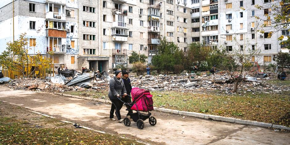 Una pareja camina con su bebé en medio de una zona atacada en Mikolaiv, ayer.