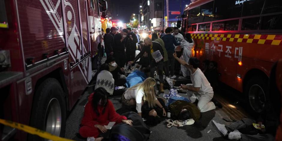 Personas heridas reciben ayuda en la calle cerca de la escena en Seúl, Corea del Sur, la madrugada del domingo 30 de octubre de 2022