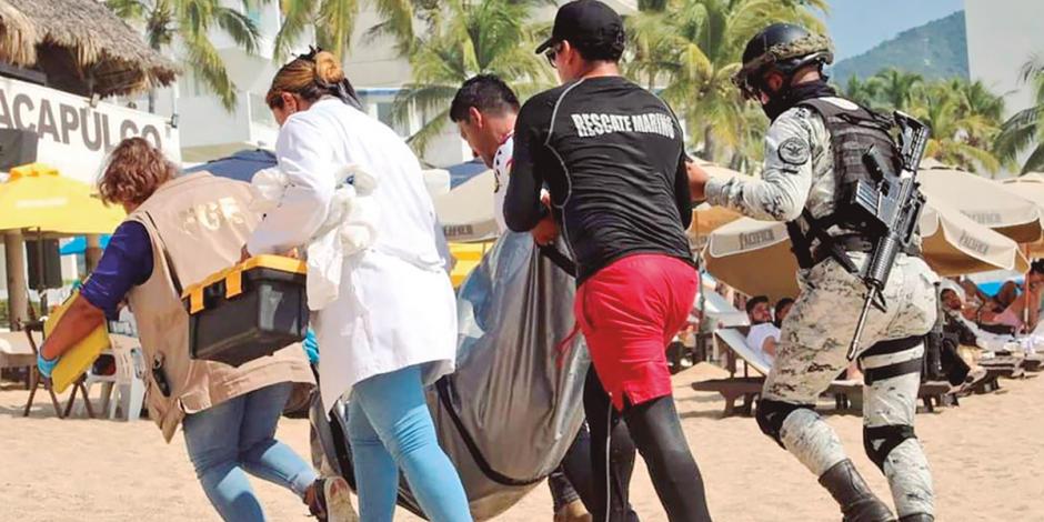 Elementos de la Fiscalía de Guerrero trasladan uno de los cadáveres encontrados este fin de semana en el puerto.