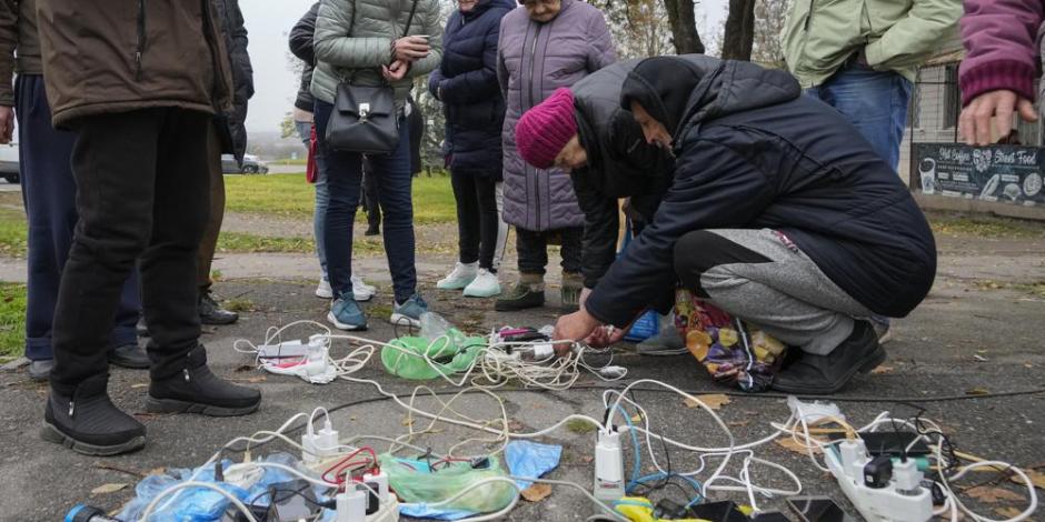 Ciudadanos ucranianos intentan recargar sus dispositivos electrónicos ante los apagones en su país, ayer.