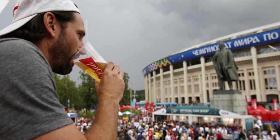 Hombre bebe una cerveza frente a la estatua de Lenin y el estadio Luzhniki, durante la Copa Mundial de futbol de 2018 en Moscú.