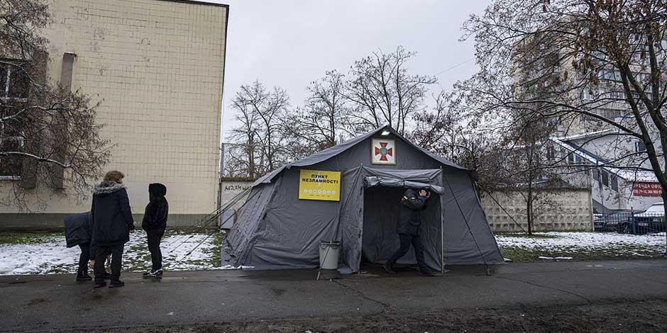Unas personas de pie frente a una tienda de campaña con calefacción en Kiev, Ucrania, el lunes 28 de noviembre de 2022