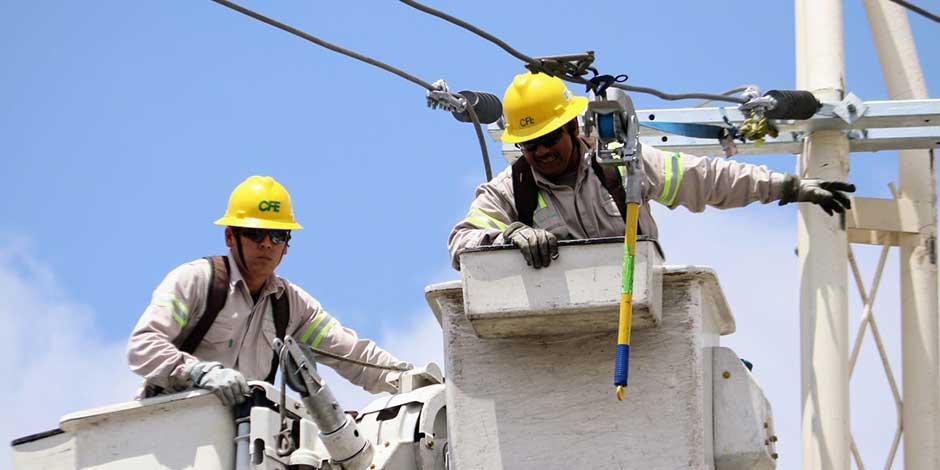 Electricistas de la Comisión Federal de Electricidad realizan trabajos de electrificación al norte de la ciudad montados en una grúa.