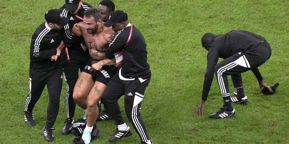 Agentes de seguridad retiran a un aficionado que invadió la cancha durante el partido entre Países Bajos y Argentina.
