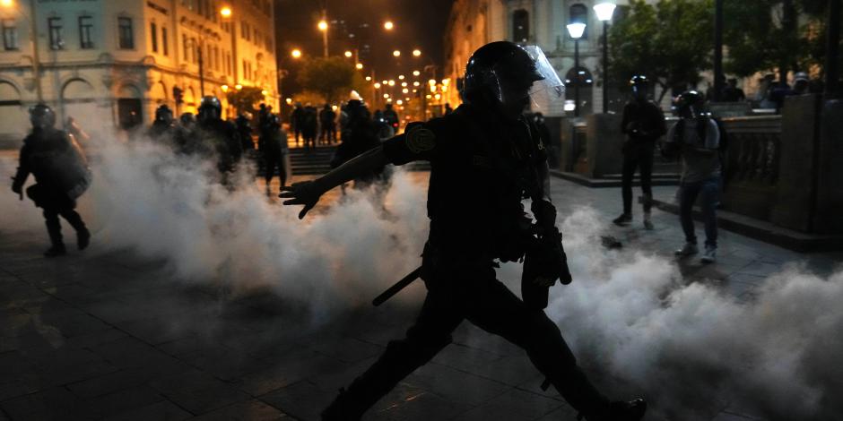 Una nube de gas lacrimógeno rodea a los policías que intentan disipar a simpatizantes del destituido presidente Pedro Castillo, el domingo 11 de diciembre de 2022, en la plaza San Martín, en Lima