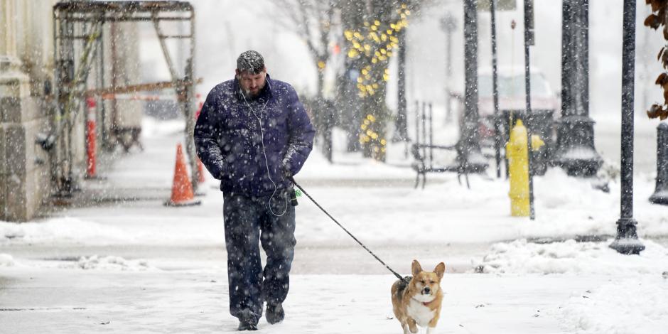 Una persona camina con su perro en una calle de Pittsfield, Massachusetts, el viernes 16 de diciembre de 2022.