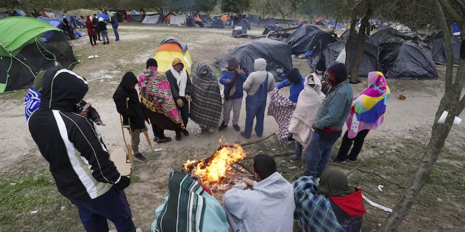 Migrantes en un campamento improvisado en Matamoros buscan calentarse alrededor de una fogata, ayer.