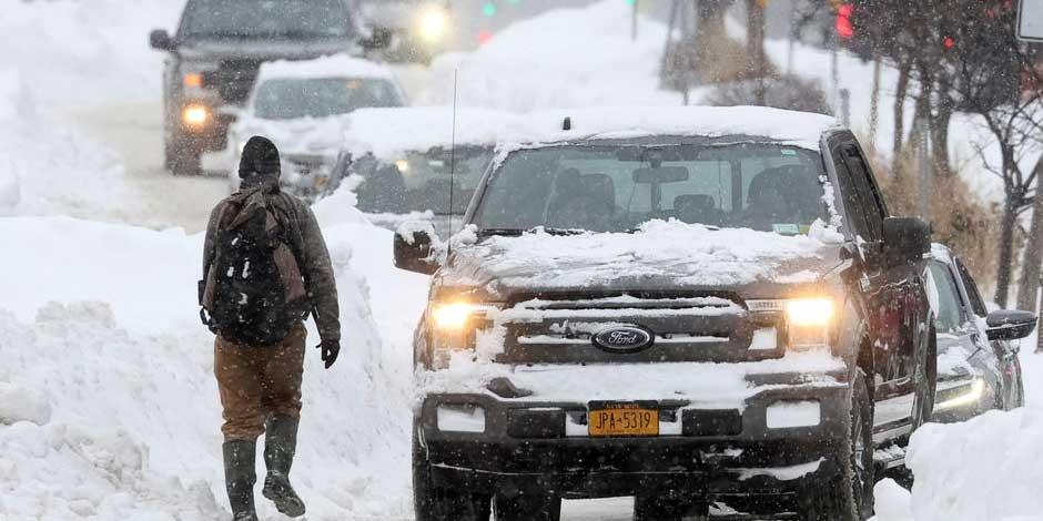 Un hombre camina por la calle mientras pasan los autos durante una tormenta de invierno que azotó la región de Buffalo, en Amherst, Nueva York, EE. UU., el 26 de diciembre de 2022.