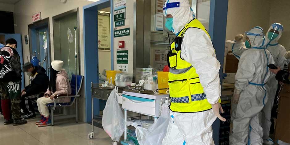 Personal de seguridad con un traje protector vigila mientras los trabajadores médicos atienden a los pacientes en el departamento de fiebre del Hospital Tongji, una importante instalación para pacientes con la enfermedad del coronavirus