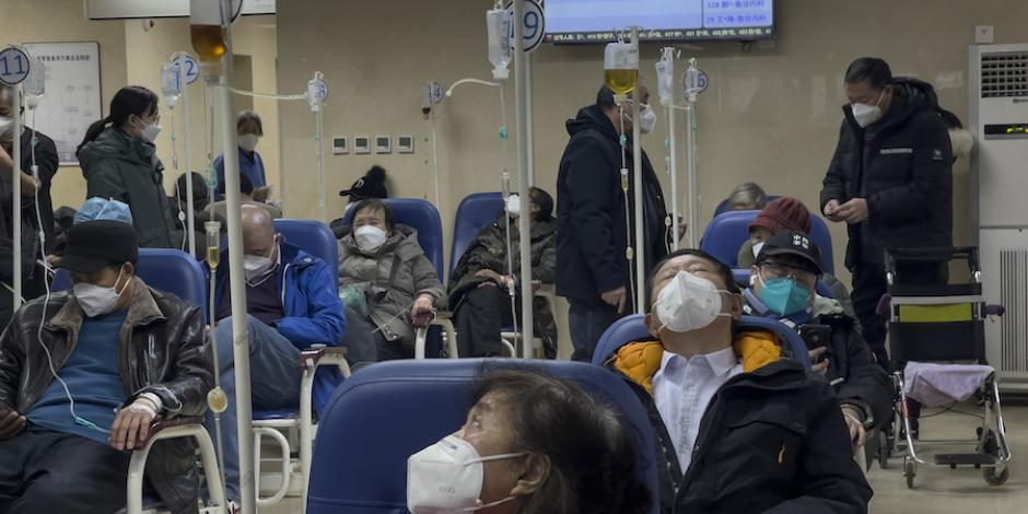Pacientes conectados a sueros esperan atención médica en salas de emergencia, en Beijing.
