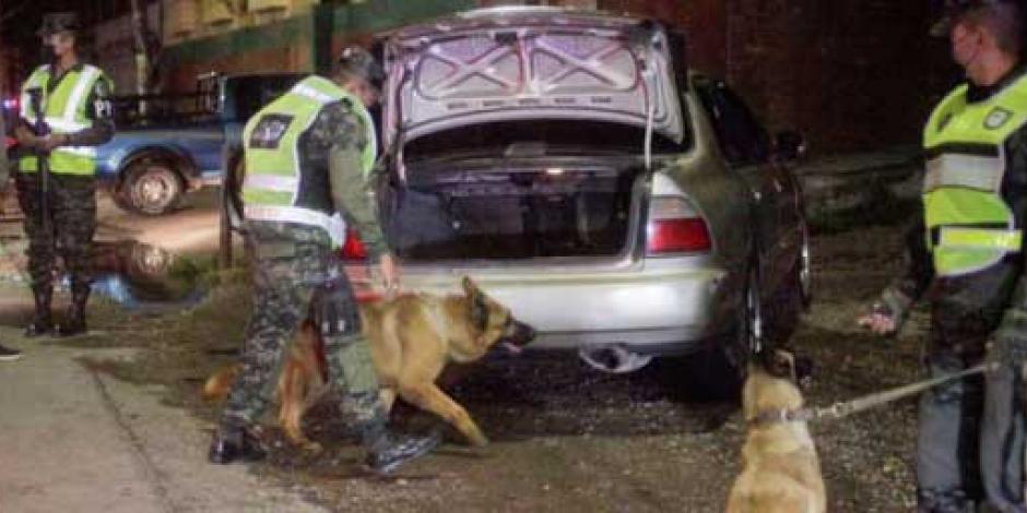 Un oficial de la Policía Militar de Honduras utiliza un perro rastreador durante una inspección de vehículos, en Tegucigalpa