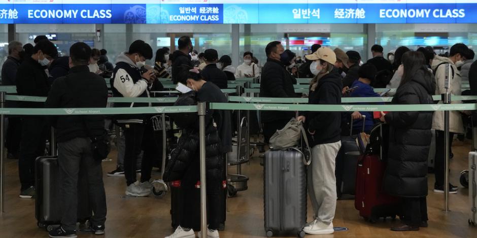 Pasajeros en Corea del Sur esperan en fila para abordar un avión hacia China, ayer.
