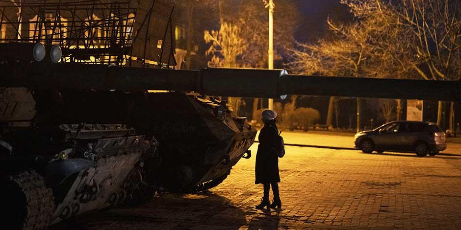 Una mujer parada frente a vehículos blindados y tanques rusos destruidos en el centro de Kiev, Ucrania, el viernes 20 de enero de 2023