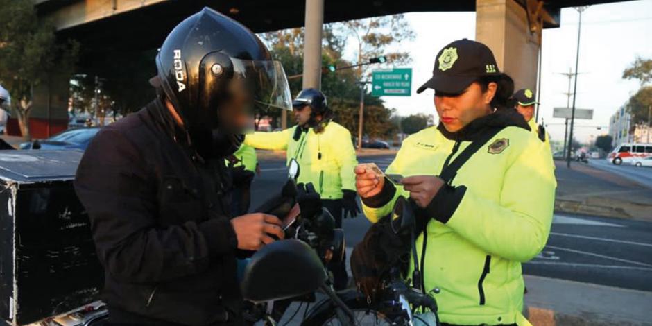 Elementos de Tránsito de la Secretaría de Seguridad Ciudadana  revisan los documentos de un motociclista en una vía primaria al continuar con los operativos, ayer.
