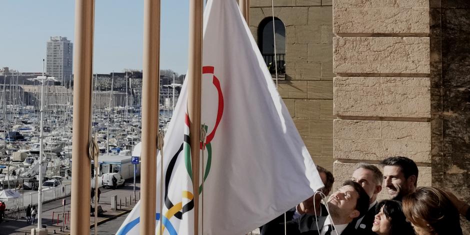El alcalde de Marsella, Benoit Payan, eleva la bandera olímpica frente al director de París 2024, Tony Estanguet.