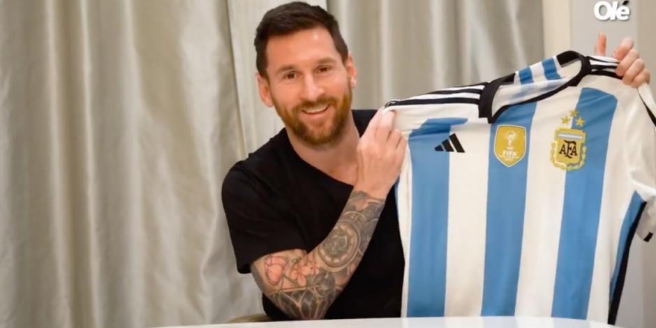 Lionel Messi posa con la nueva playera de Argentina con las tres estrellas de campeón del mundo.