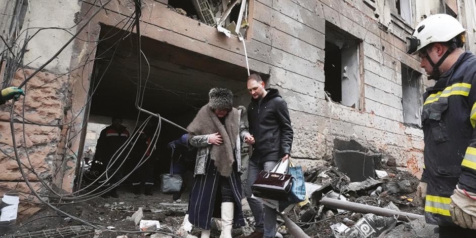 Personal de emergencia ayuda a una ciudadana a salir de un edificio bombardeado en Járkov, ayer.