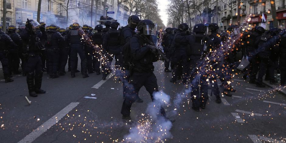 Policías antimotines en sus puestos mientras les lanzan proyectiles en una manifestación contra los planes de reformar el sistema de pensiones de Francia, en París, el sábado 11 de febrero de 2023. (AP Foto/Michel Euler)