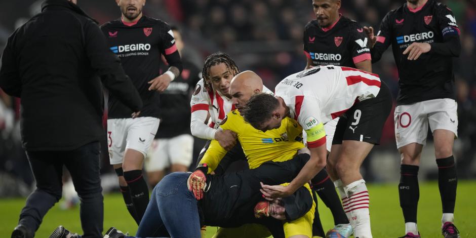 Jugadores intervienen después de que un aficionado del PSV atacó al portero del Sevilla Marko Dmitrovic en el encuentro de la Europa League