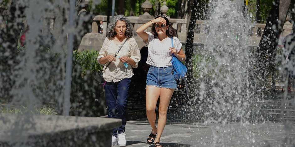 Dos mujeres caminan por la calle en un día caluroso
