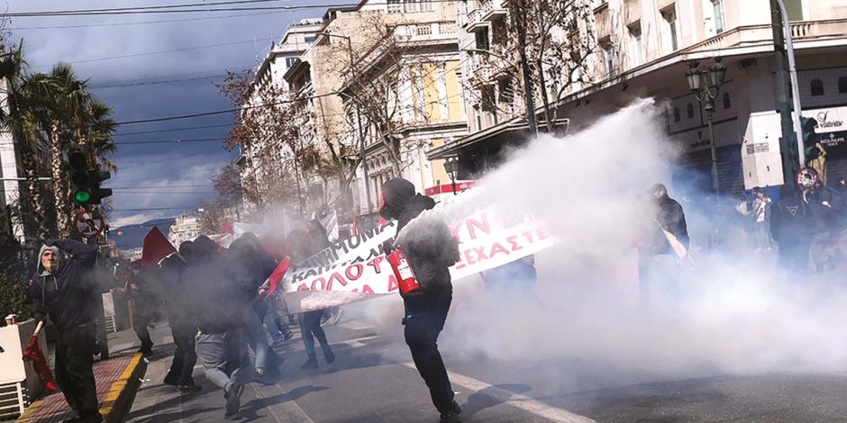 Un manifestante acciona un extintor contra un grupo de policías en las calles de Atenas, ayer.