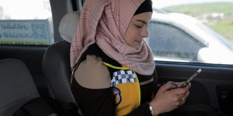 Salam Mahmoud, voluntaria de la Defensa Civil de Siria (Cascos Blancos), mira su teléfono móvil mientras viaja en un vehículo, en la provincia de Idlib.
