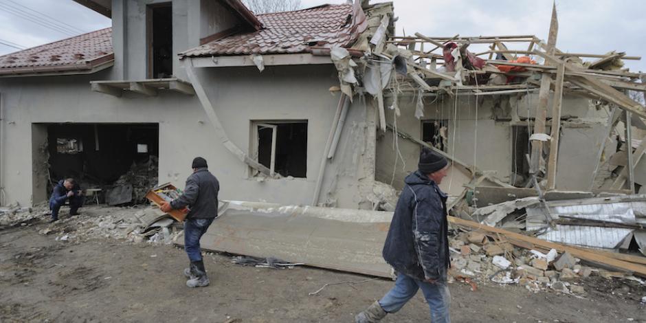 Residentes de Leópolis recogen escombros en uno de los edificios alcanzados por un misil, ayer.