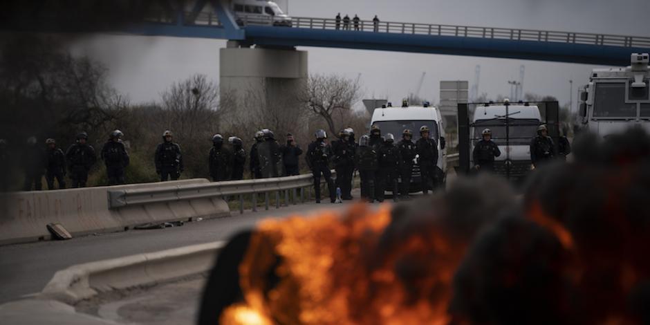 Policías observan una pila de llantas quemadas dejadas por manifestantes frente a un depósito de petróleo, ayer, en Fos-sur-Mer, al sur de Francia.
