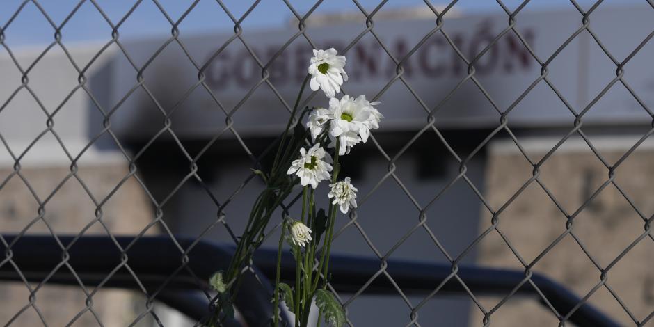 Flores marchitas cuelgan de la cerca frente a un centro de detención de inmigrantes donde decenas de personas murieron en un incendio en Ciudad Juárez, México,