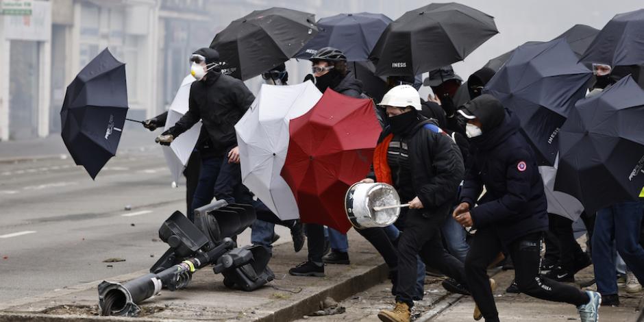 Armados con paraguas disidentes franceses se protegen del gas lacrimógeno, en París, ayer.