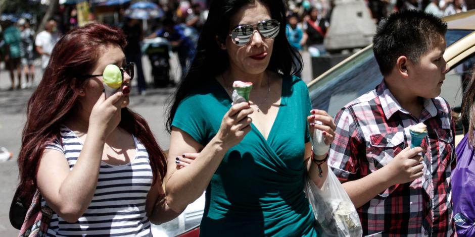 Turistas disfrutan de un helado para combatir el fuerte calor que se siente en la ciudad de México.