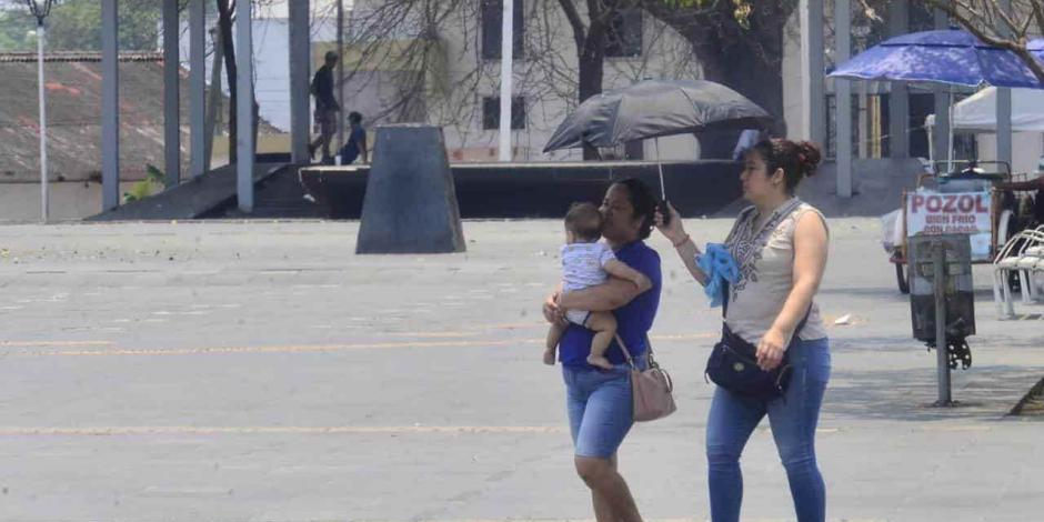 Dos mujeres y una bebé se protegen del sol en Villahermosa, la capital del estado de Tabasco, en donde el termómetro alcanzó los 35 grados Celsius, ayer.