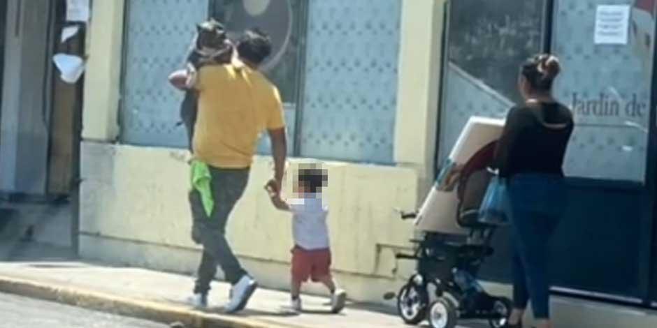 Padre carga a perro en sus brazos mientras su hijo camina