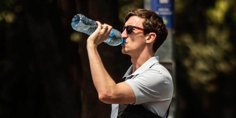 Un hombre en la calle toma agua directo de una botella para mitigar el calor