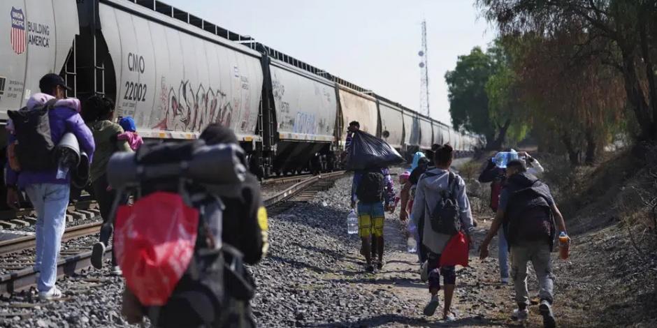 Migrantes caminan junto a un tren con dirección al norte, esperando poder subirse a él, en Huehuetoca, México, el viernes 12 de mayo de 2023.