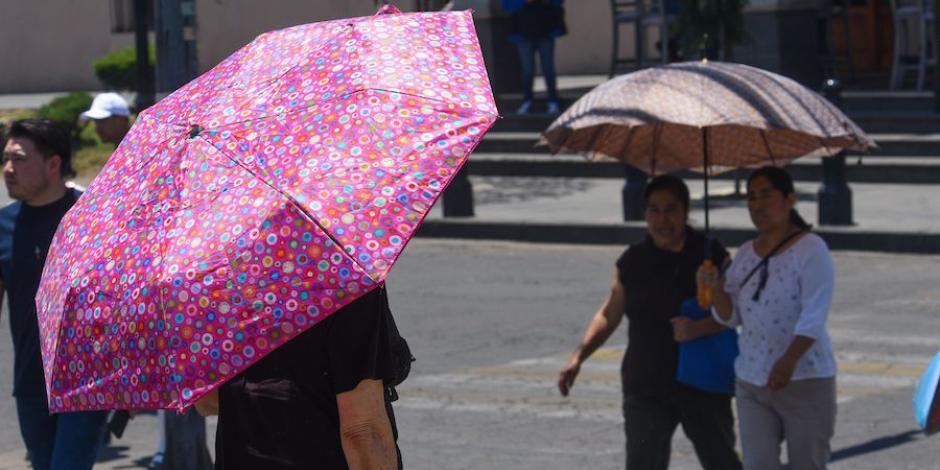 Varias personas se protegen del sol con sombrillas en la capital, ayer.