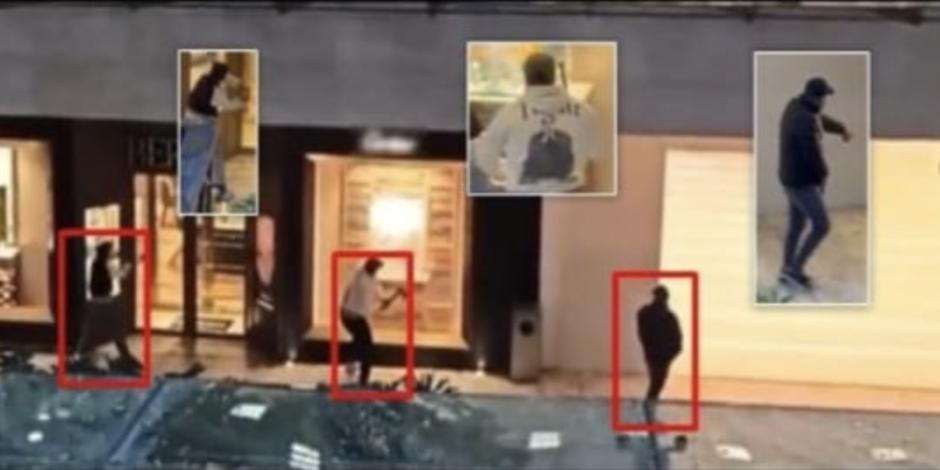 Tres hombres proceden a romper los cristales de los mostradores, mientras otro vigila con un arma en la mano.