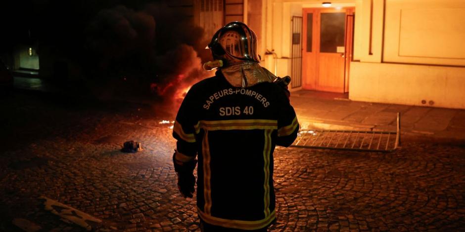 Un bombero francés trabaja para extinguir una moto en llamas durante el quinto día de protestas en Francia.