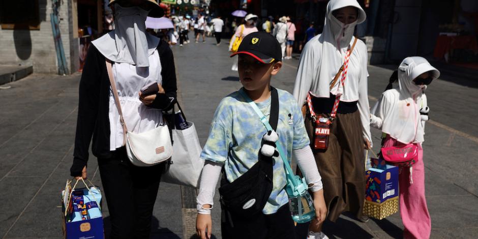 Residentes de China salen completamente cubiertos ante el calor intenso, ayer.