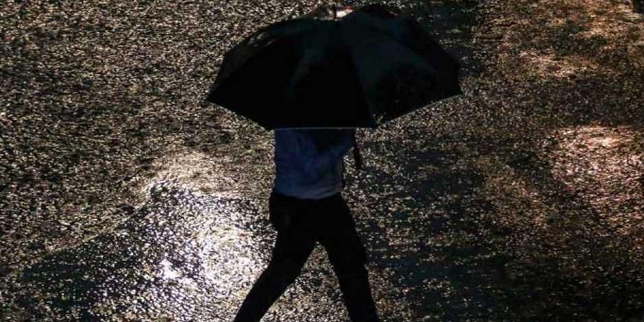 Una persona camina bajo la lluvia cubriéndose con su paraguas
