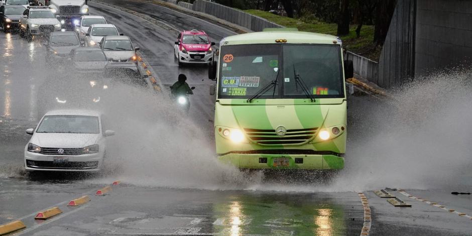 Una unidad del transporte público circula por una avenida en un día lluvioso