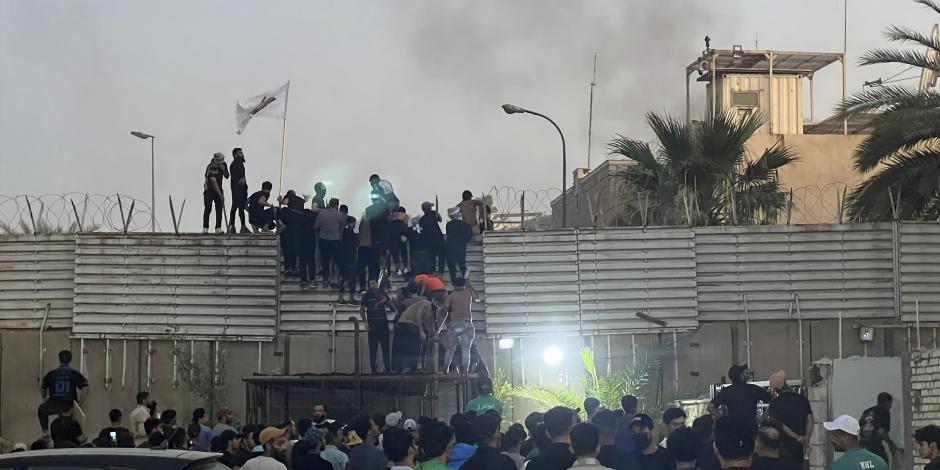 Manifestantes trepan un muro en la embajada sueca de Bagdad, el jueves 20 de julio de 2023. Manifestantes airados por la quema de un ejemplar del Corán irrumpieron en la embajada sueca en Bagdad, donde provocaron un pequeño incendio.